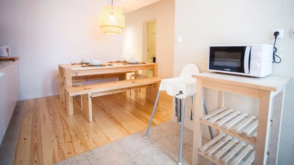 Comedor con una mesa de madera y un microondas sobre una encimera cercana.