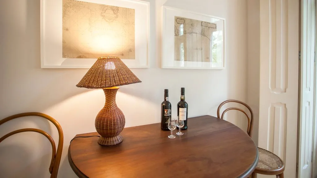 Una mesa redonda de madera con una lámpara encendida y cuadros en una zona de comedor.
