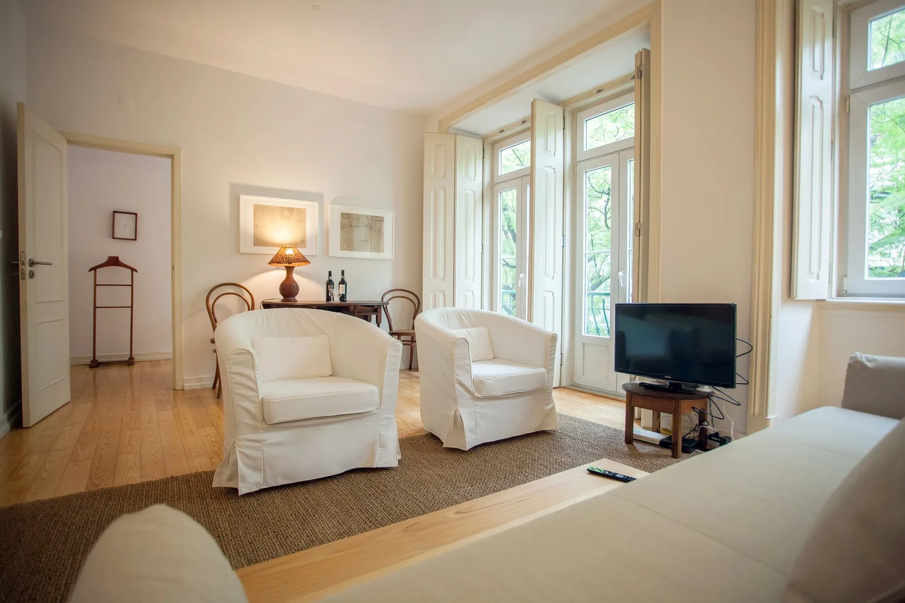 A bright living room with seating beside tall windows.