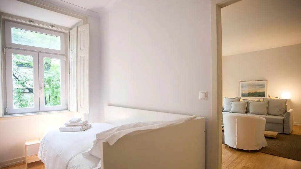 Un dormitorio luminoso con una cama junto a una ventana grande.