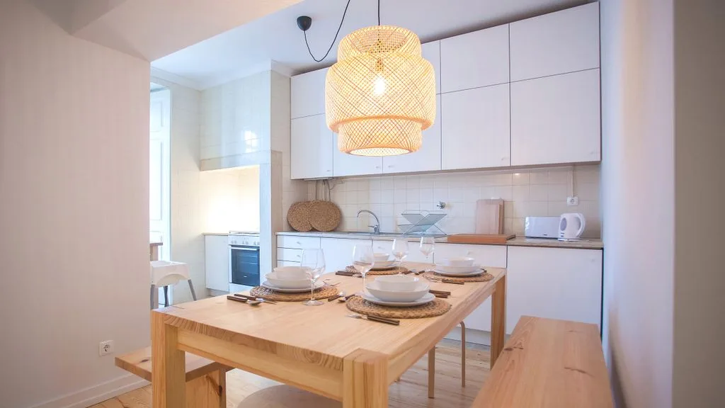 A bright dining area with a wooden table set beneath a woven pendant light.