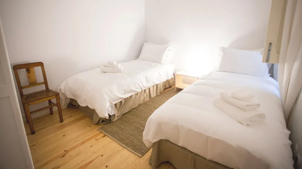 Un dormitorio con dos camas y una silla de madera.