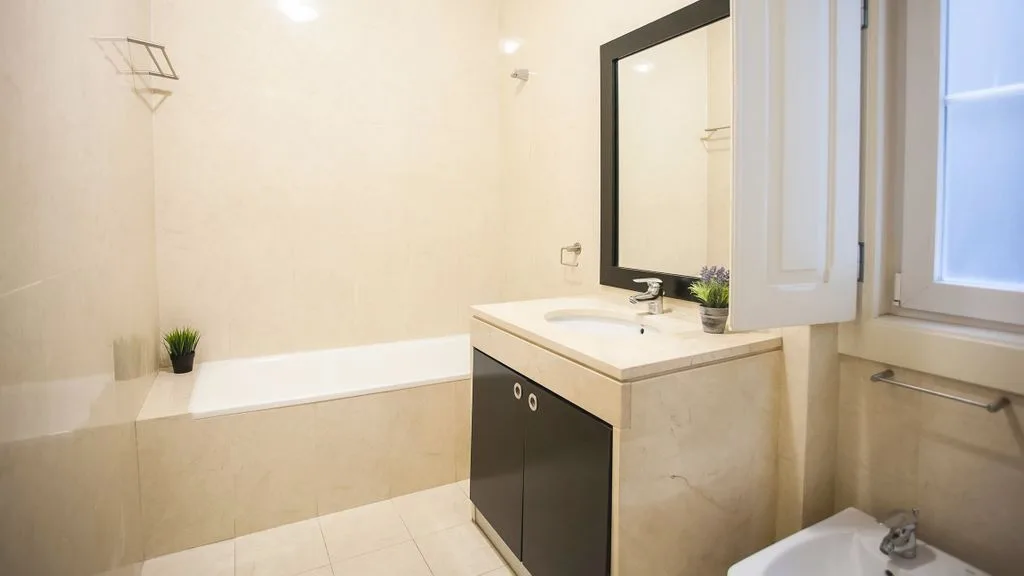 Un baño con bañera, mueble de lavabo y espejo.