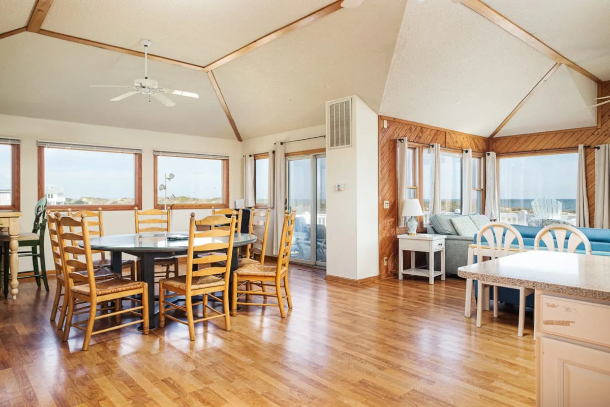 Una luminosa zona abierta de comedor y sala de estar con grandes ventanas y una mesa de comedor.
