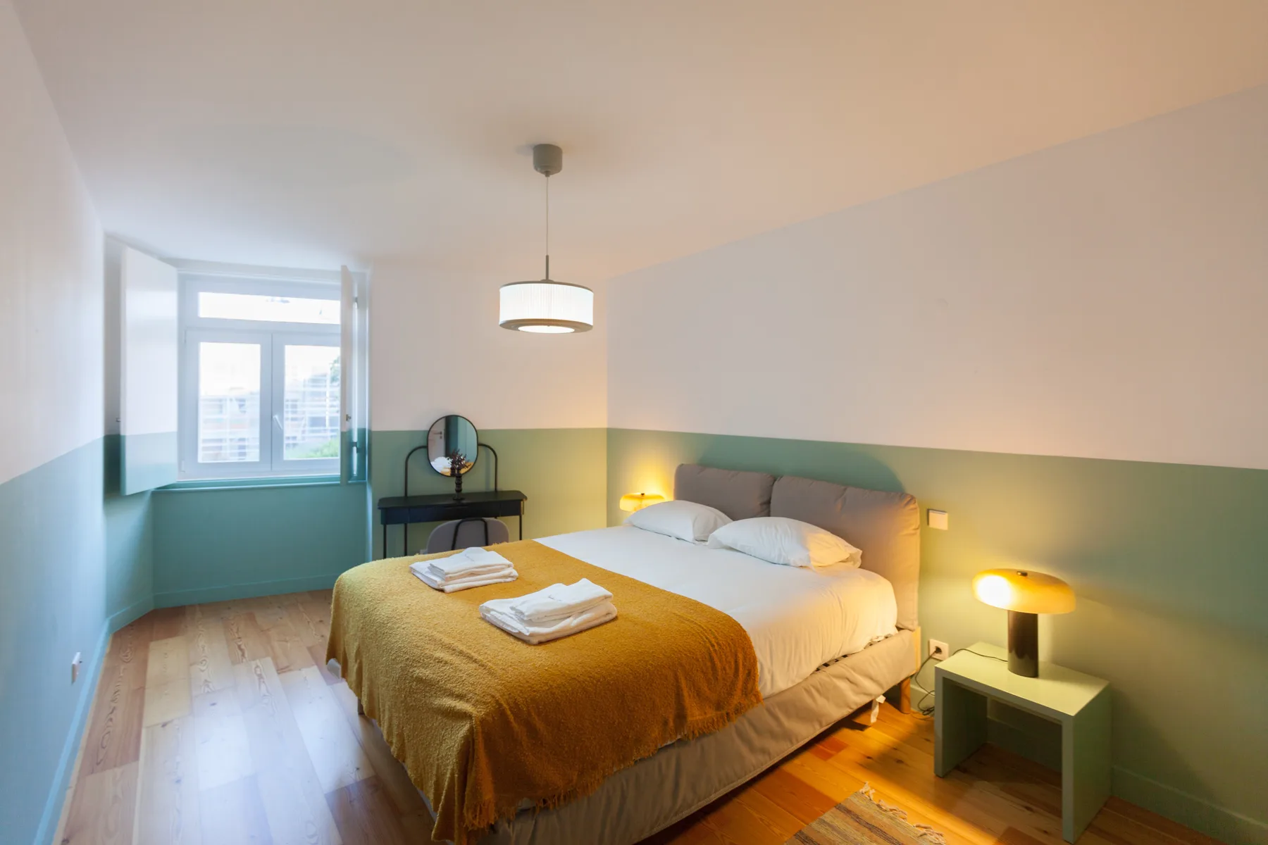 A bedroom with a bed, bedside tables, and a window.