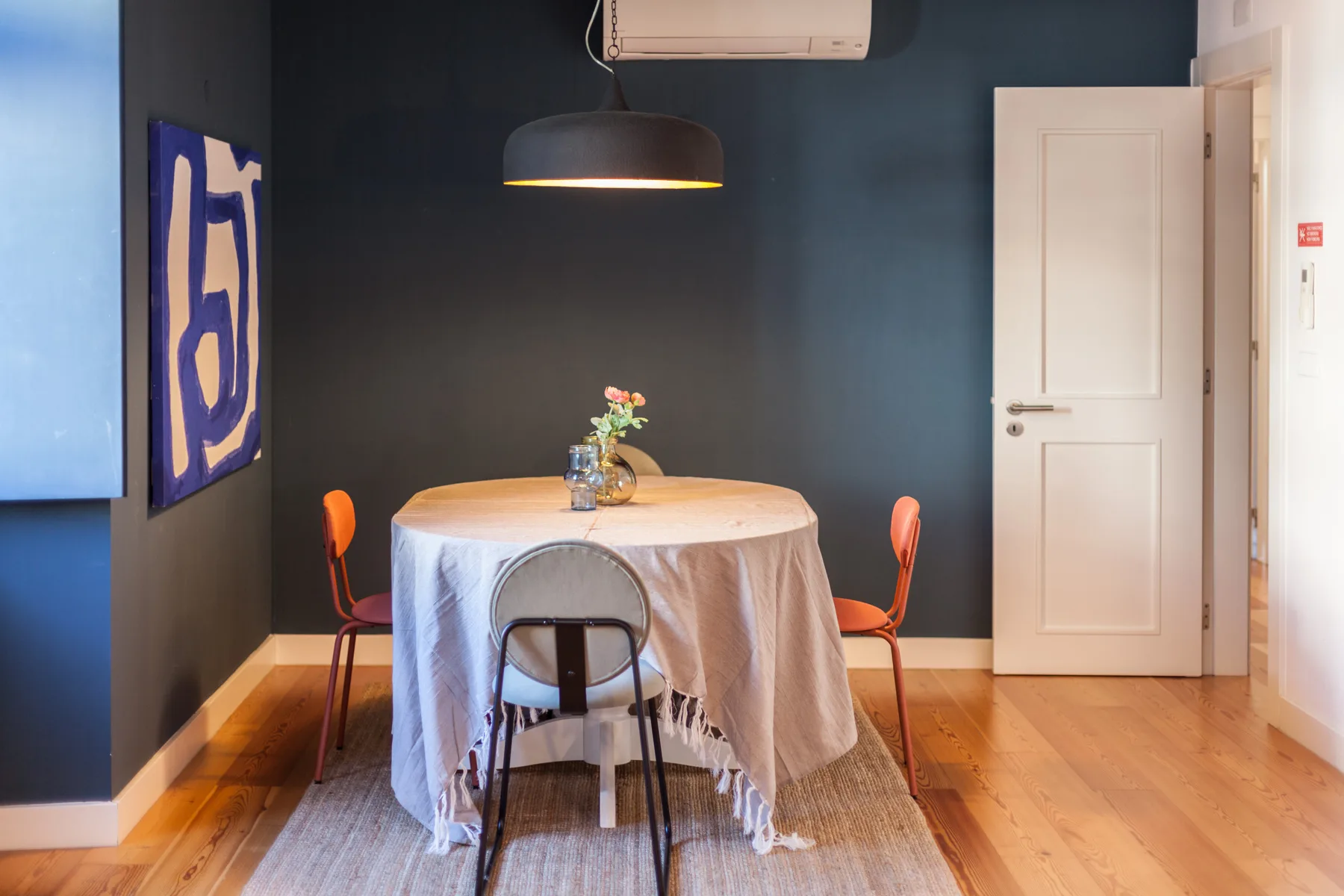 A dining area with a round table, chairs, and a hanging light.