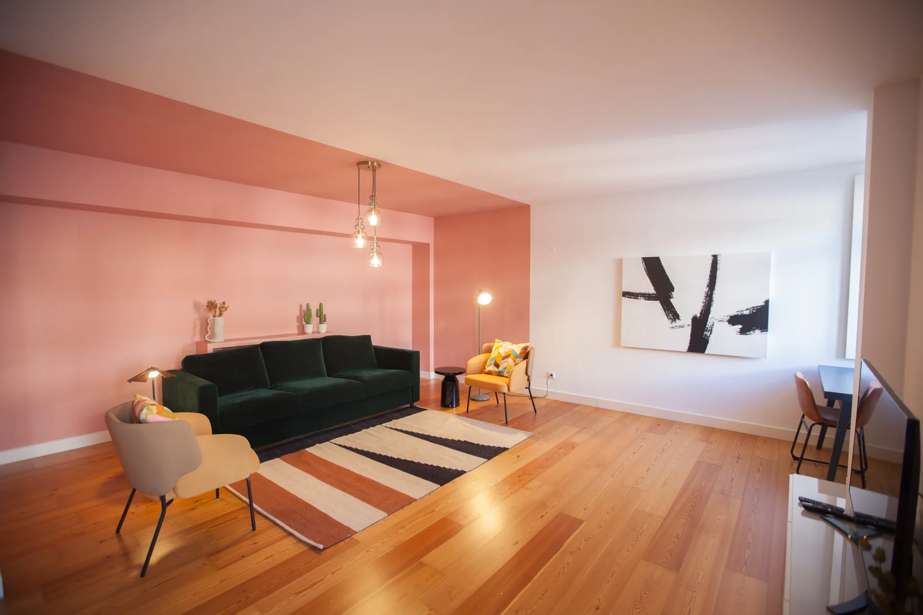 A living room with a dark sofa, a colorful rug, and wall art.