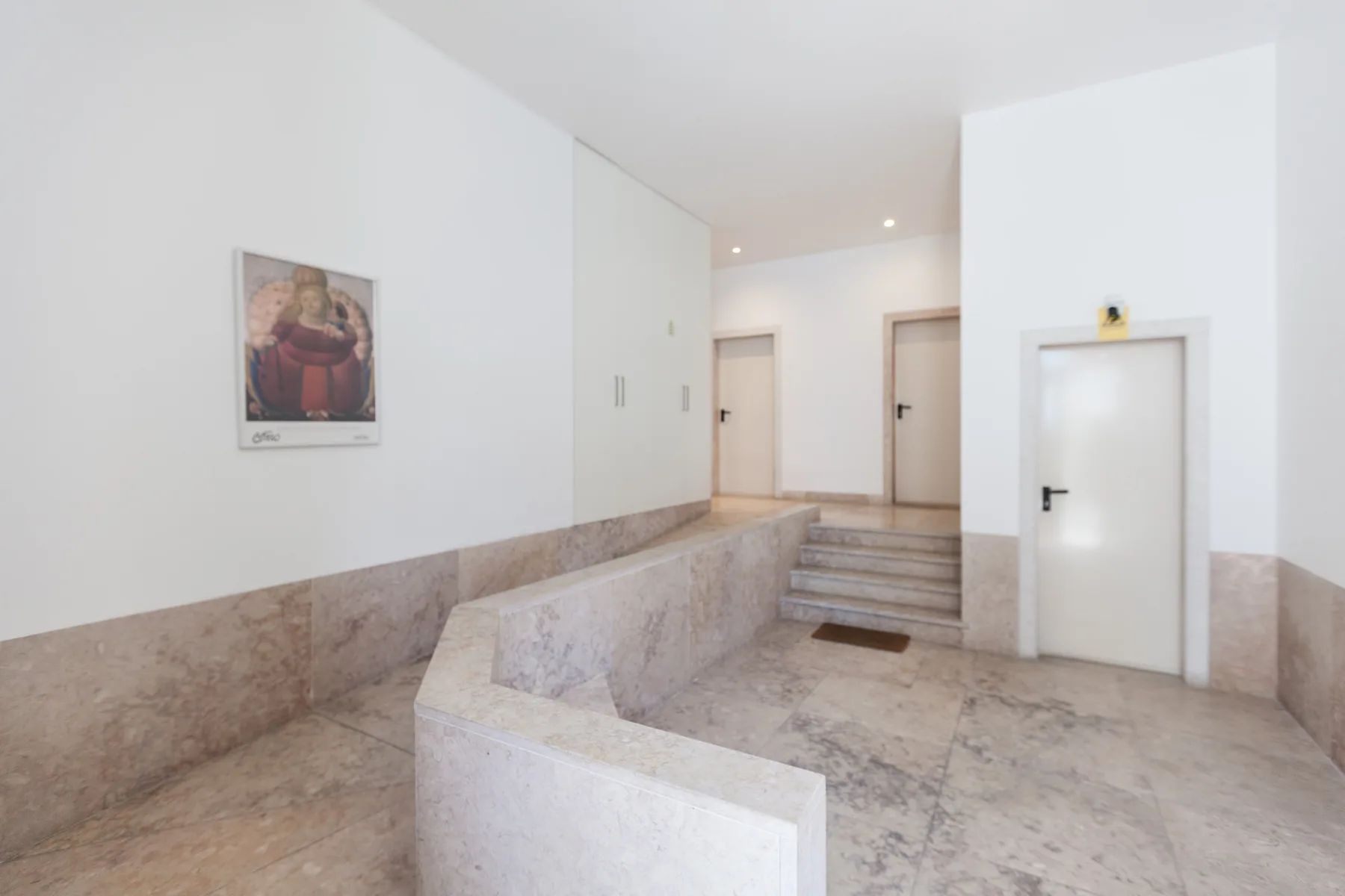 An interior hallway with pale stone walls and a short flight of steps.
