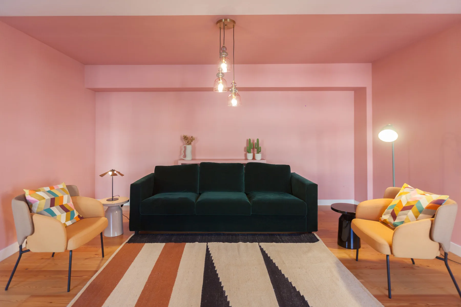 A living room with dark seating, two armchairs, and a striped rug.
