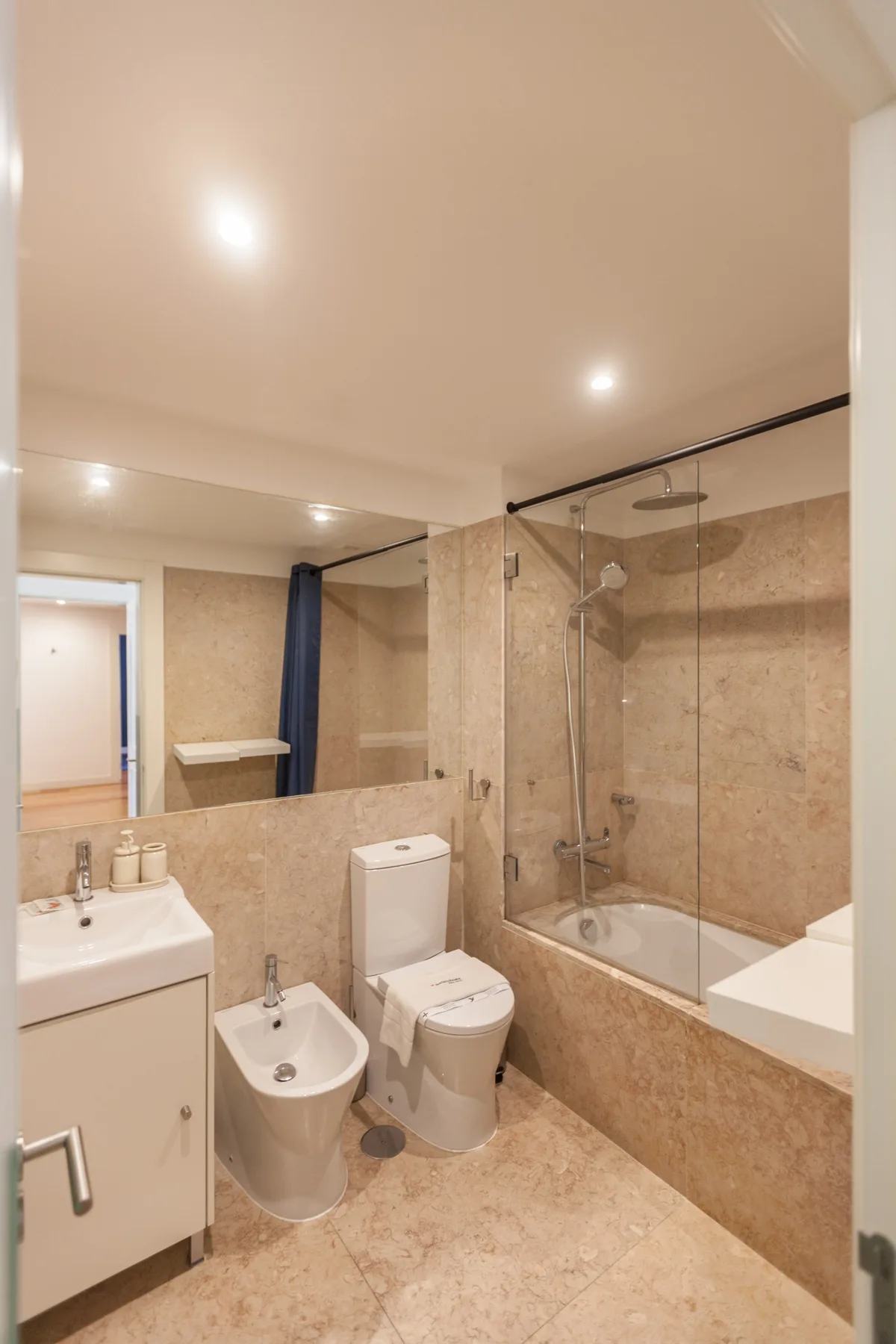 A bathroom with a bathtub, glass shower screen, sink, and toilet.