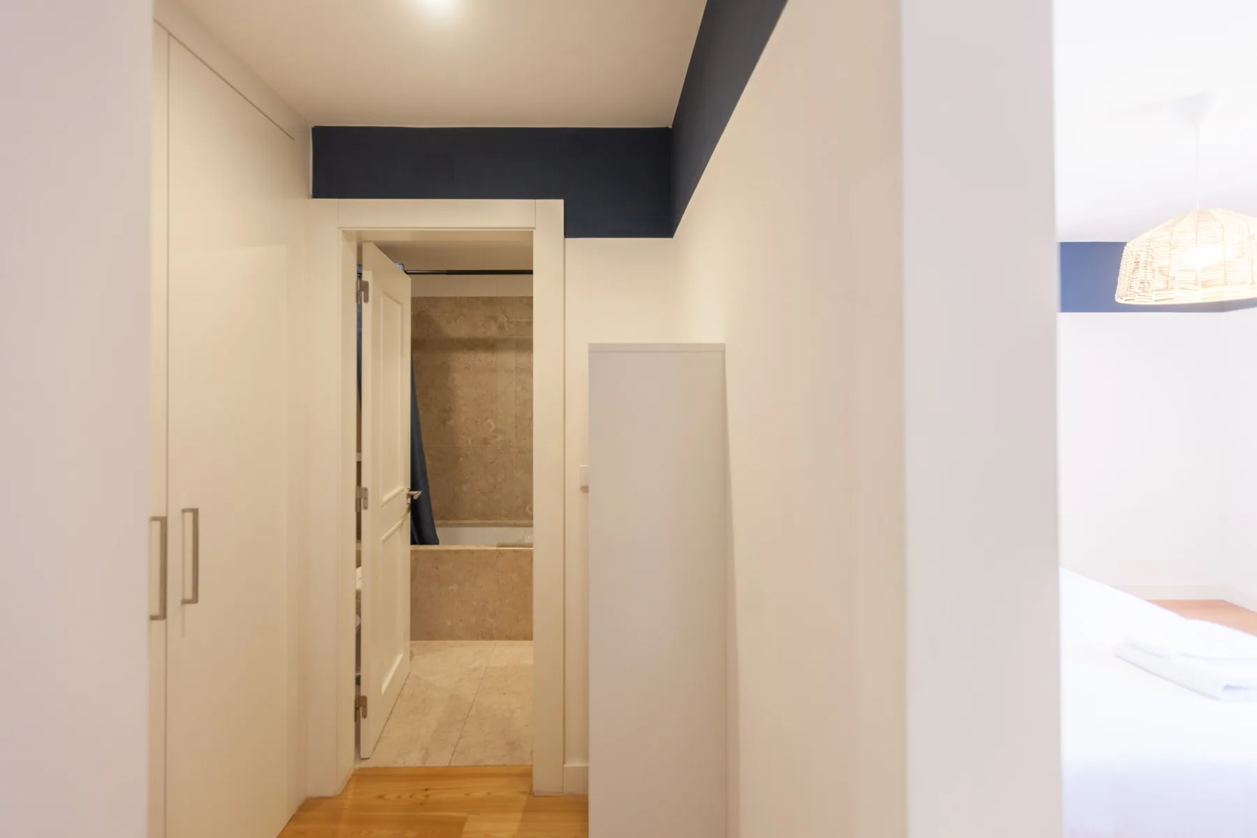A bright hallway with built-in cupboards and an open doorway to a bathroom.