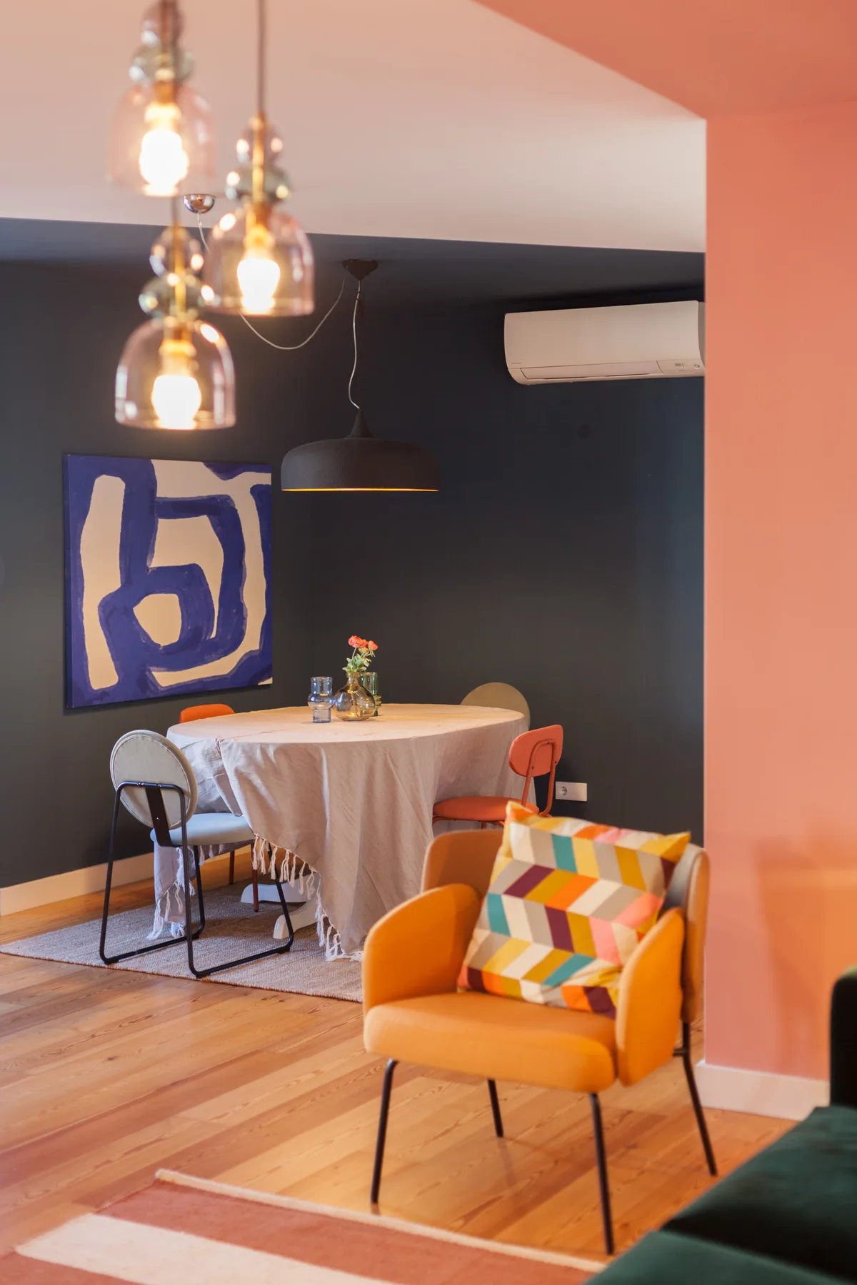 Dining area with a table and colorful seating in a room with pendant lights.