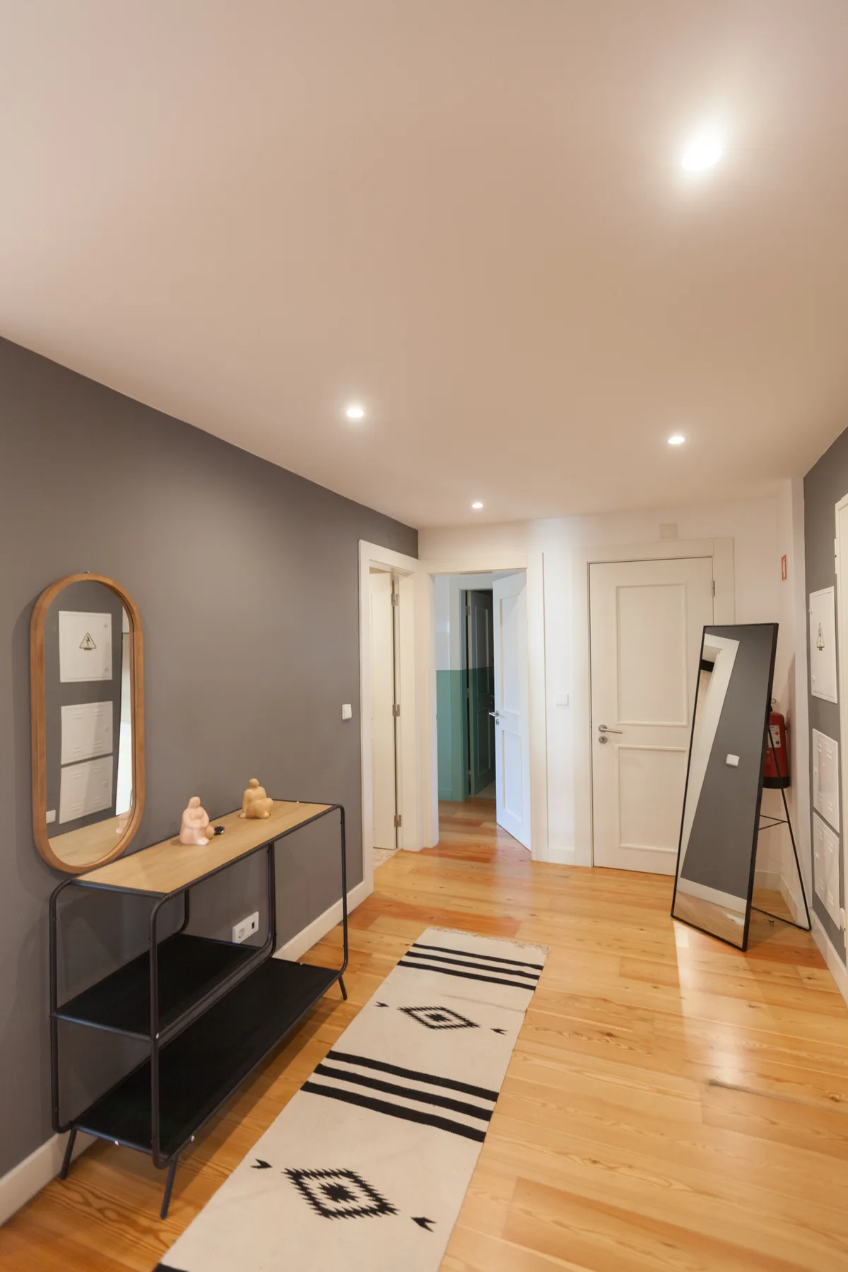 A bright hallway with wood flooring, a console table, and a patterned runner.