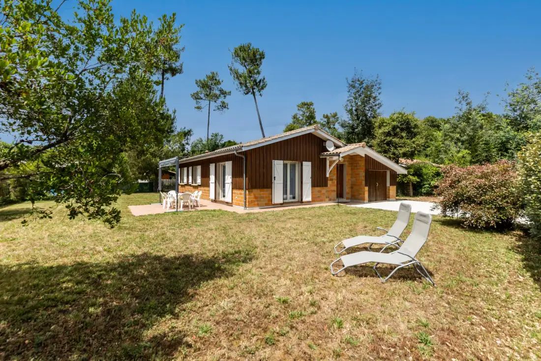A single-story house sits in a grassy yard with outdoor seating.