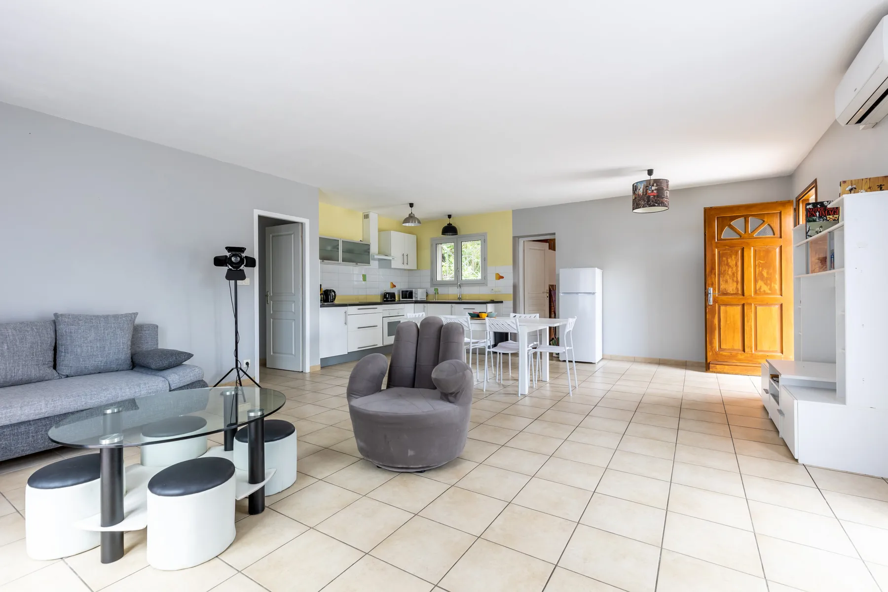A bright open-plan living area with seating, a dining table, and a kitchen.