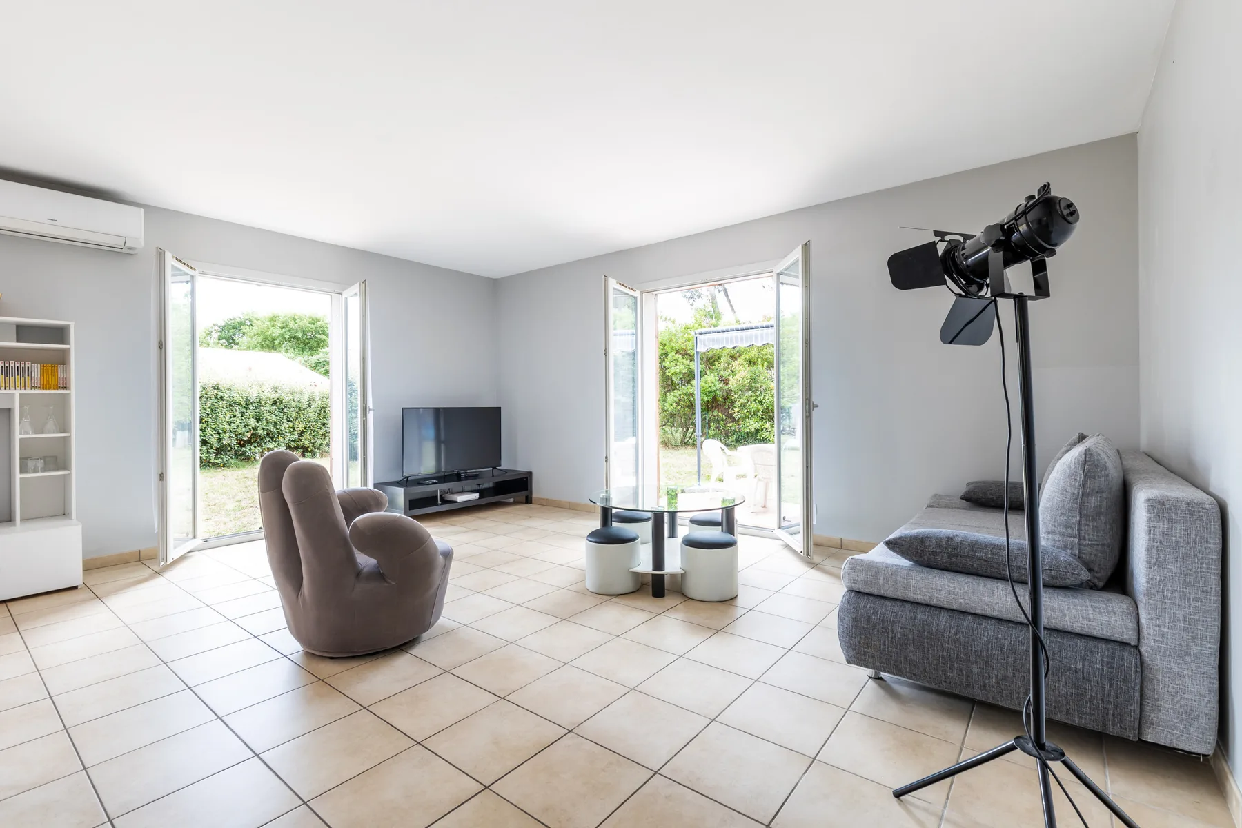 Living room with seating, a television, and open doors to the garden.