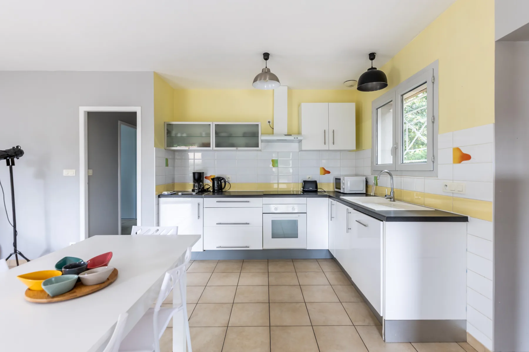 A bright kitchen with white cabinets and a dining table.