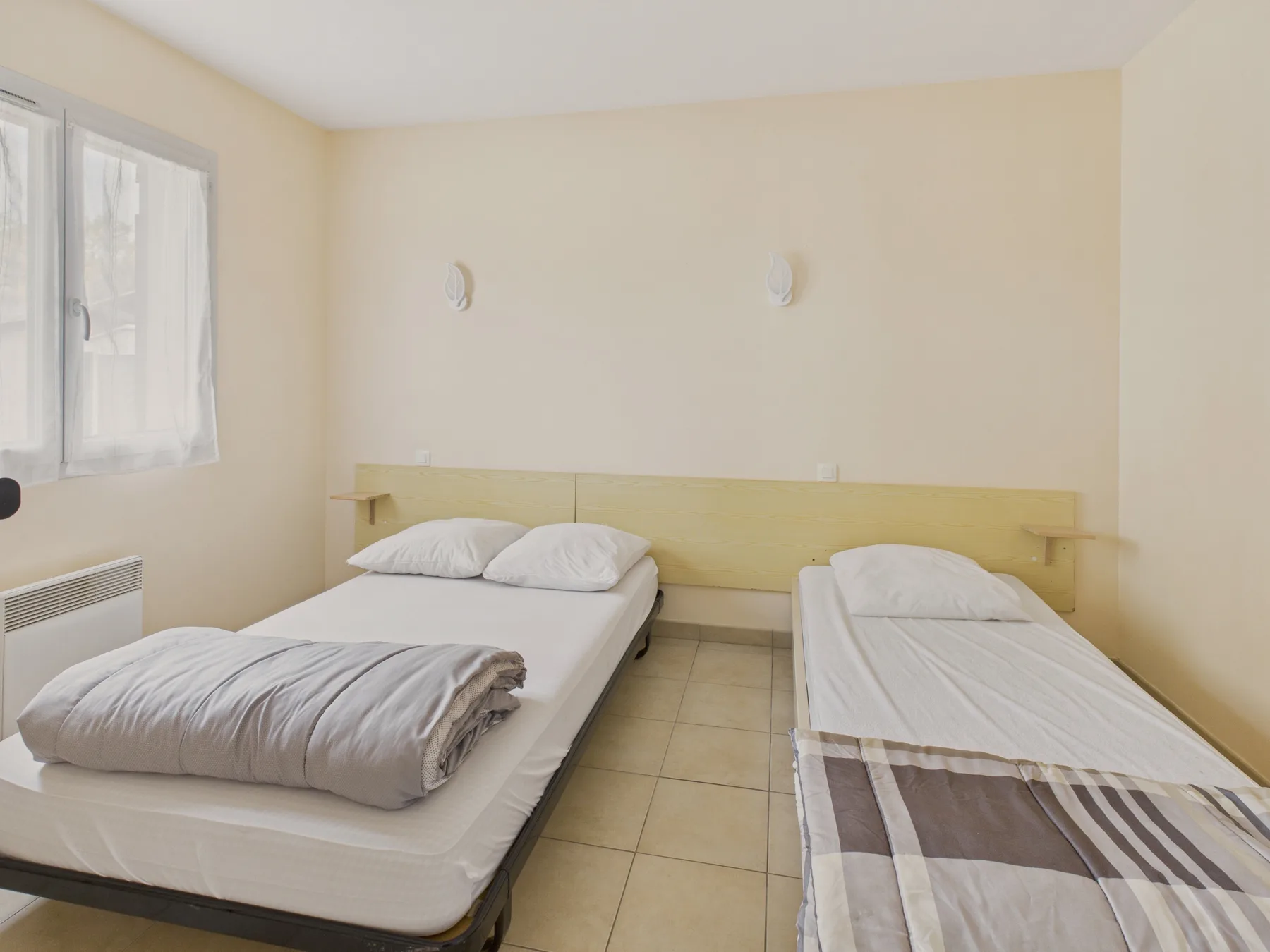 A bedroom with two single beds and a window.