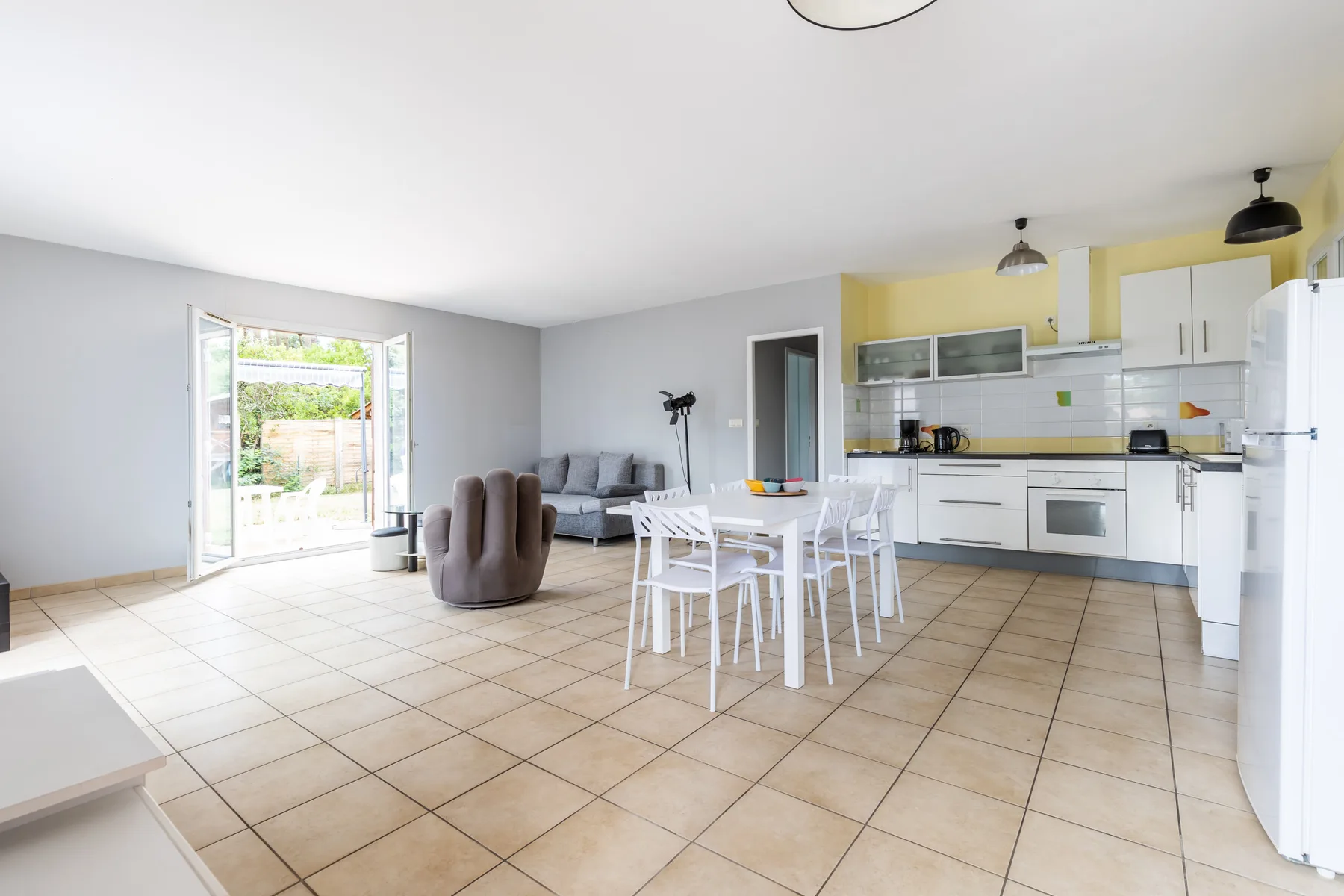 A bright open-plan living and dining area with a kitchen along the back wall.