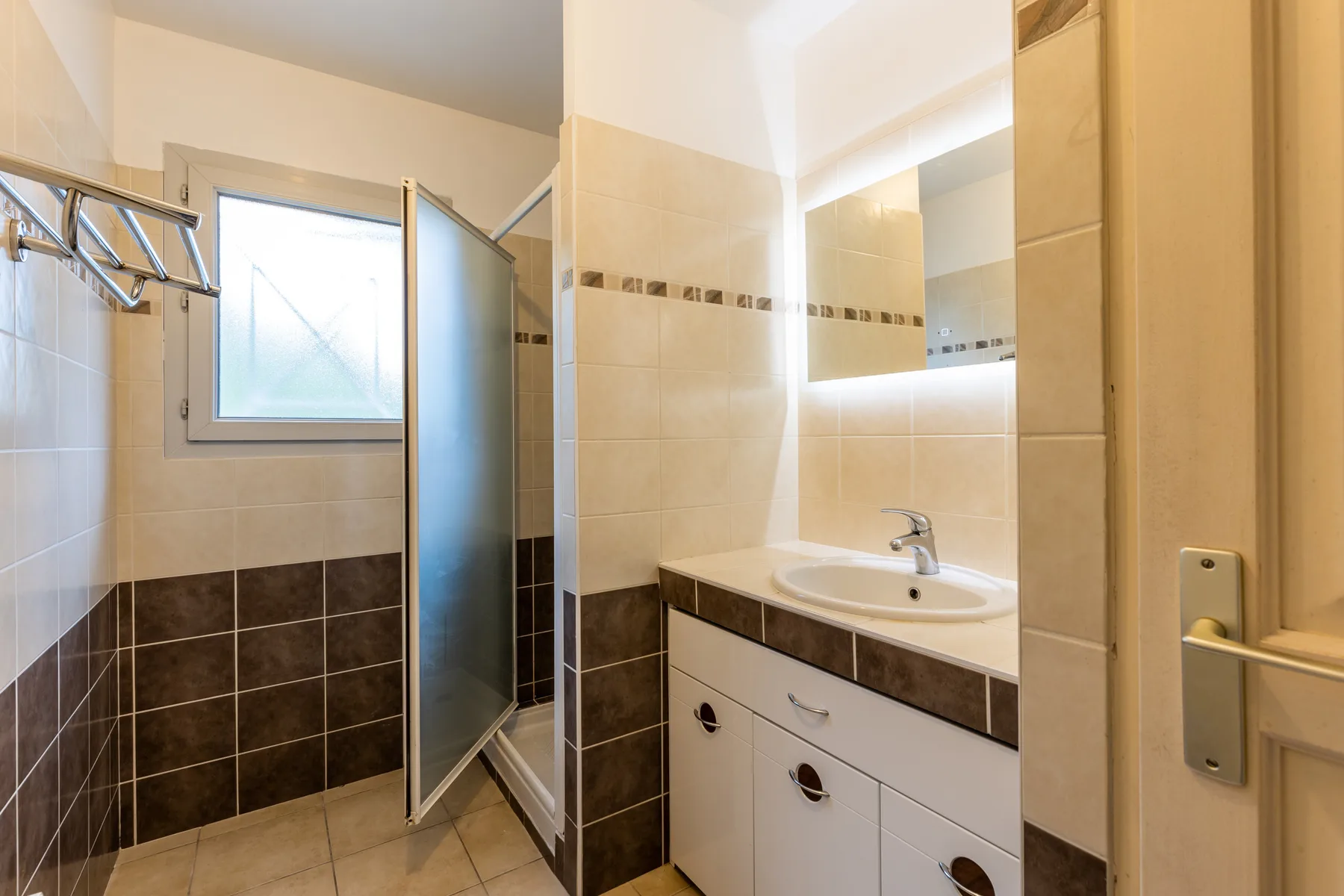 A tiled bathroom with a shower, sink, and mirrored cabinet.