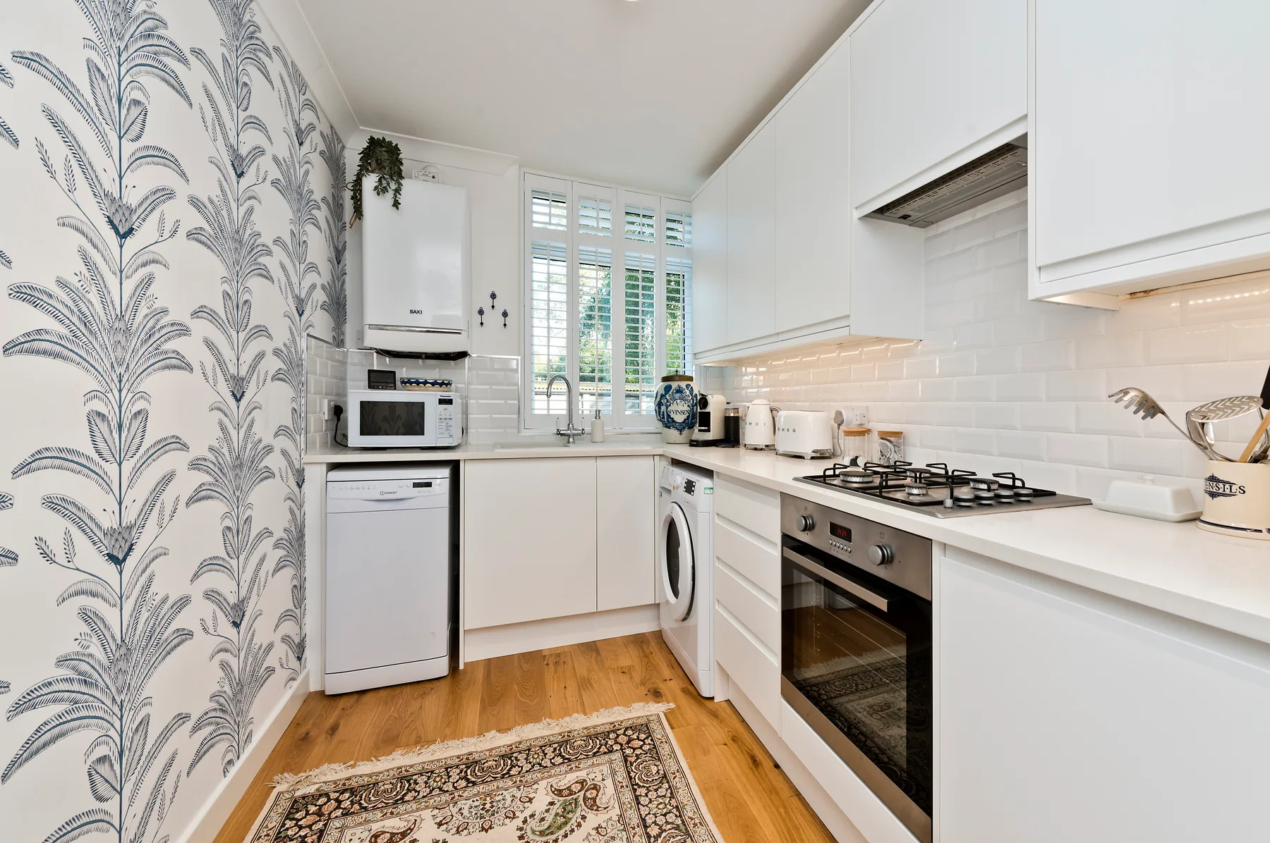 A bright kitchen with white cabinets, a window, and wood flooring.
