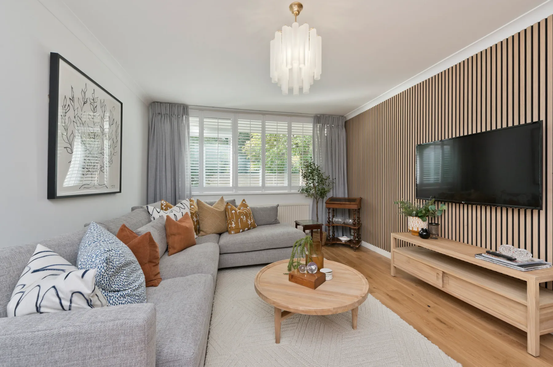 A living room with a sectional sofa, round coffee table, and wall-mounted television.