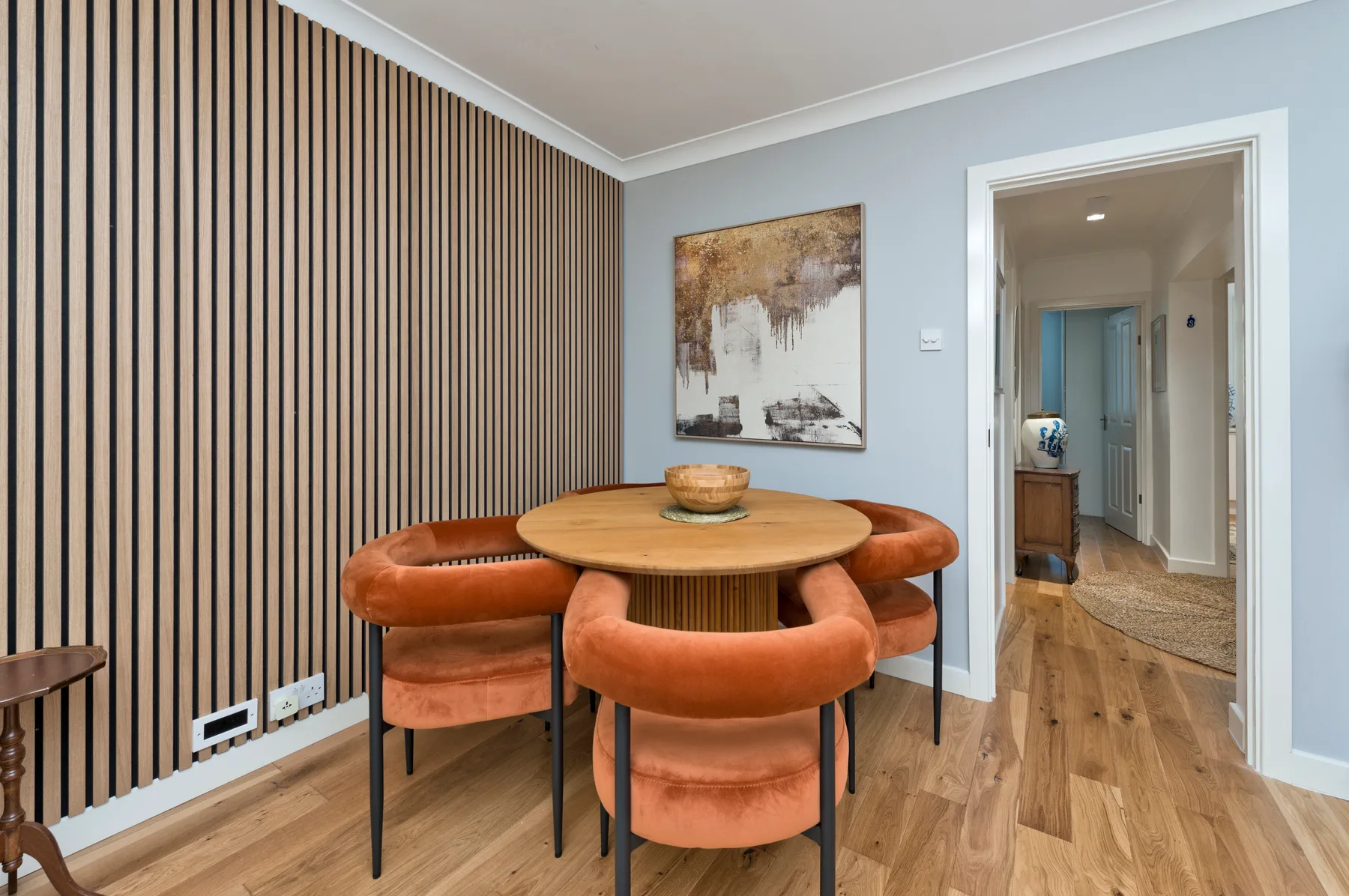 A dining area with a round wooden table and upholstered seating.