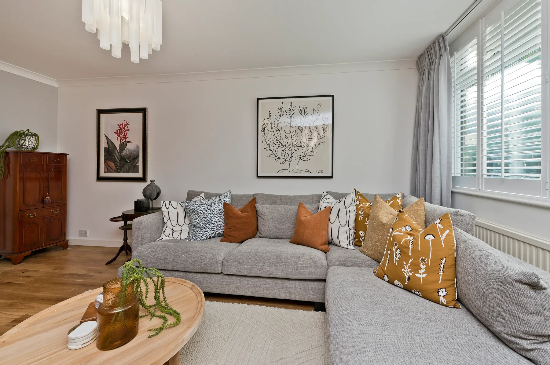 Living room with a gray sectional sofa and botanical artwork.