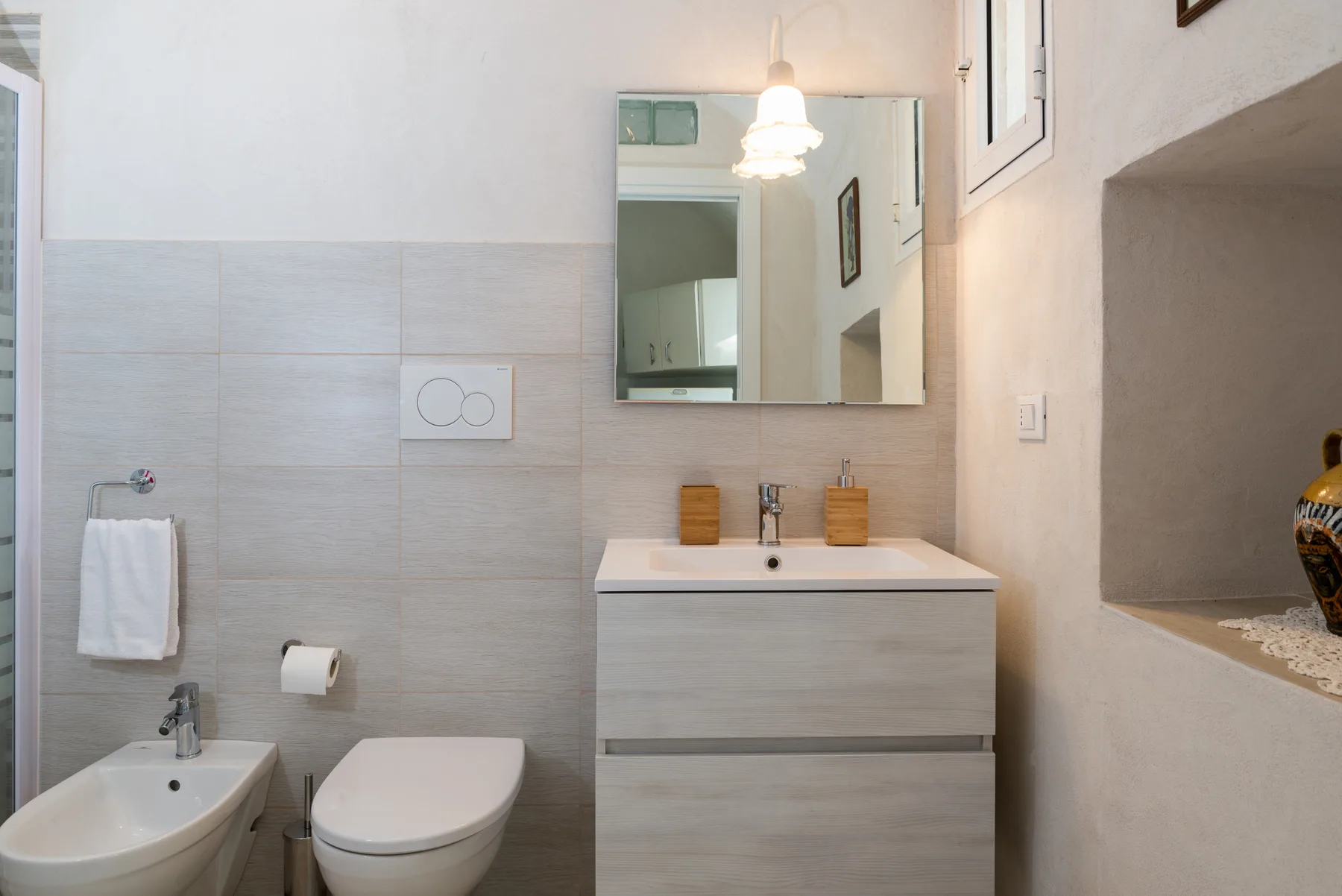 A bright bathroom with a sink, toilet, and wall mirror.