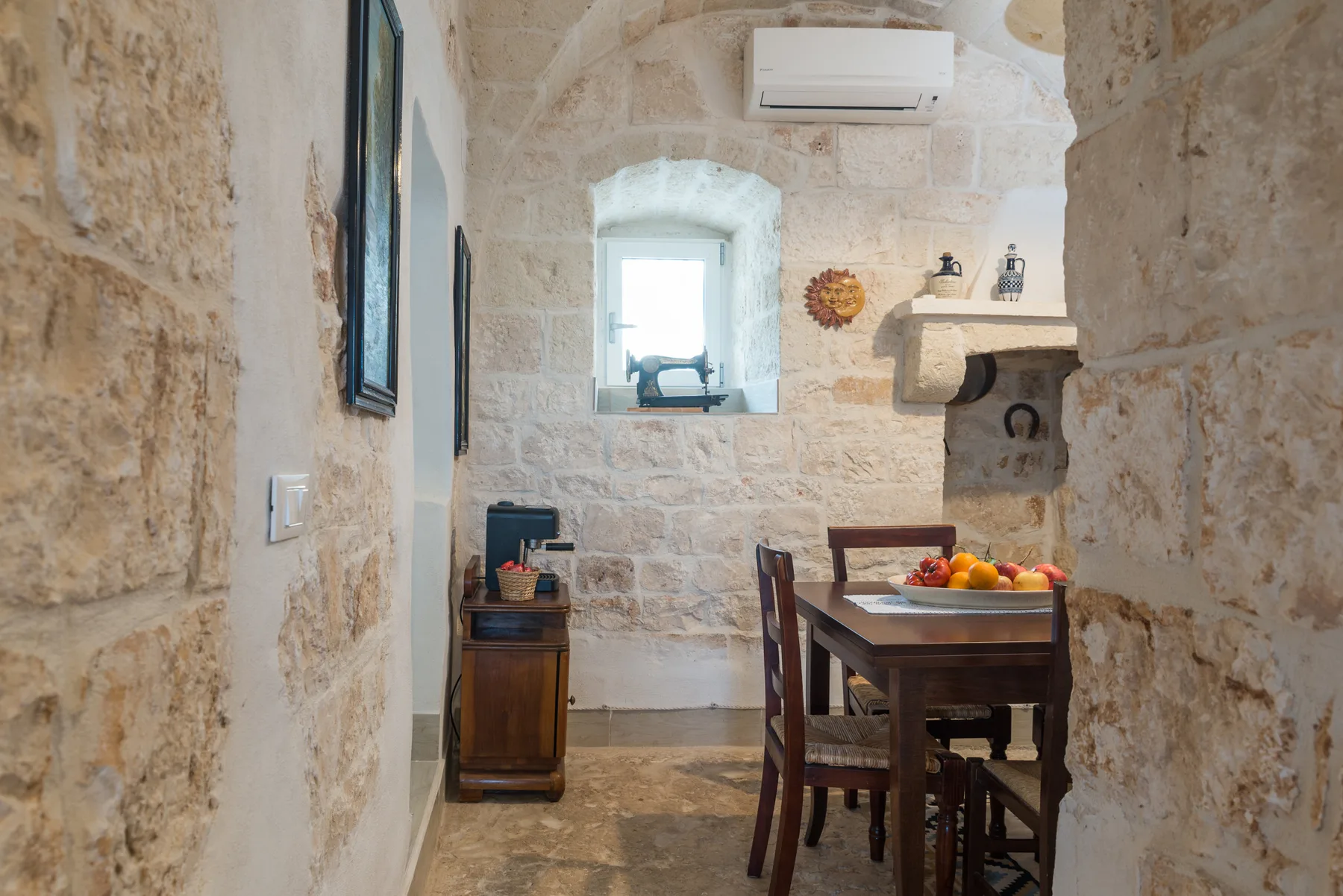 A stone dining room with a wooden table set with a bowl of fruit.