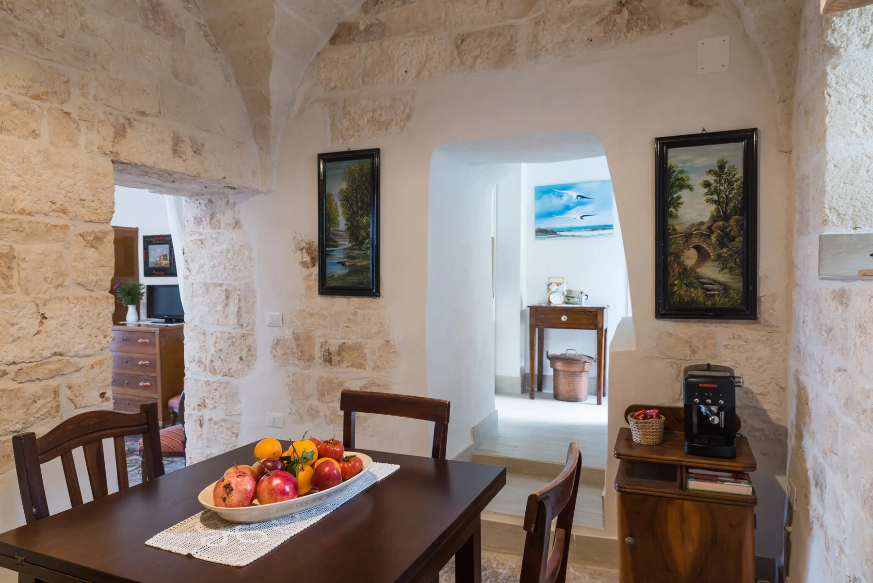 A stone dining room with a dark wooden table and fruit centerpiece.