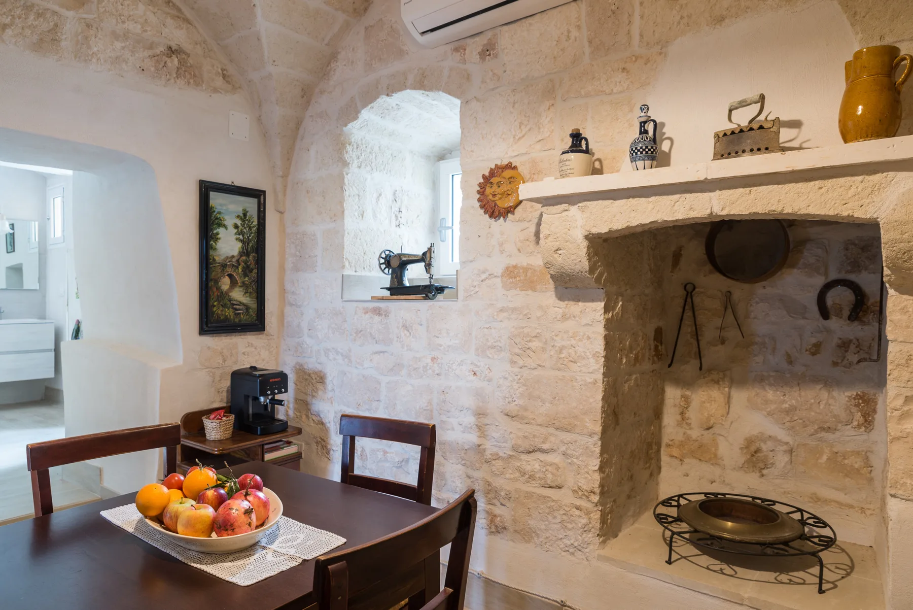 A stone-walled dining room with a wooden table set with a bowl of fruit.