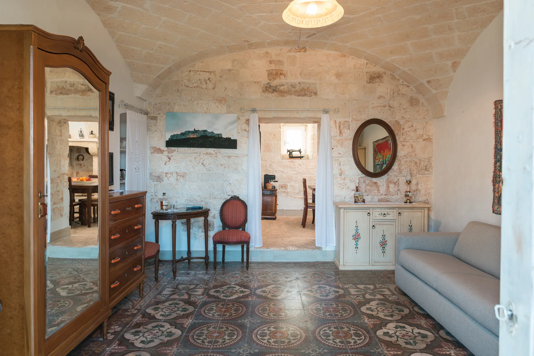 A bedroom with a tiled floor, a bed, and a mirrored wardrobe.