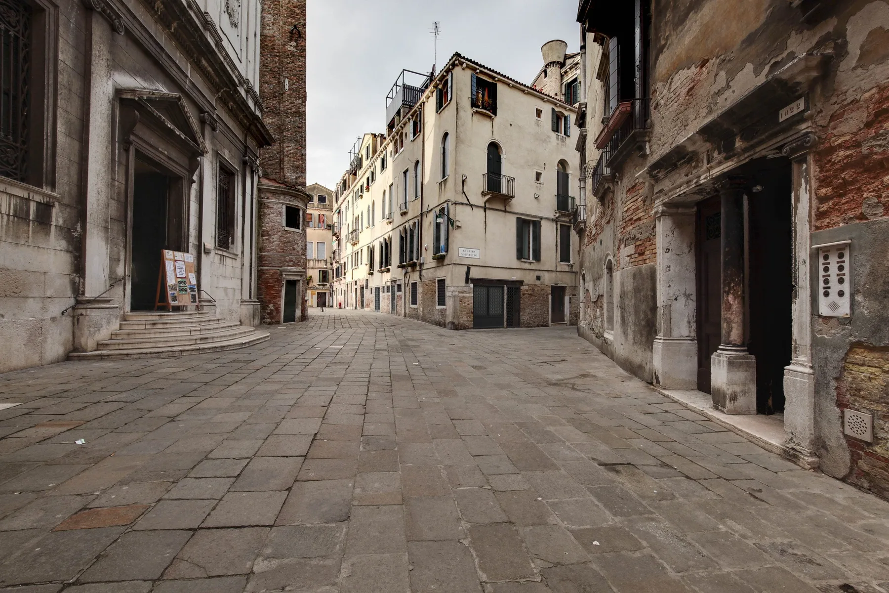 A paved pedestrian street runs between old buildings in a historic-looking urban scene.