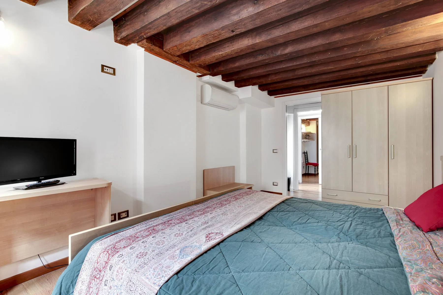 A bedroom with a bed, a television, and a wardrobe.