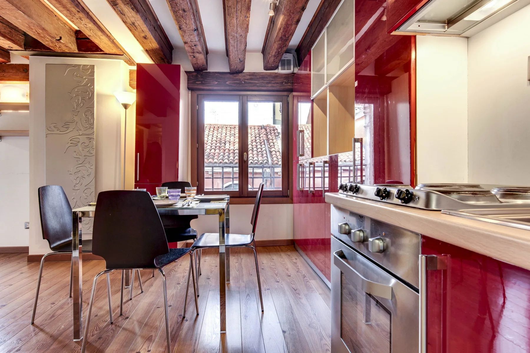 A kitchen with a dining table and exposed wooden ceiling beams.