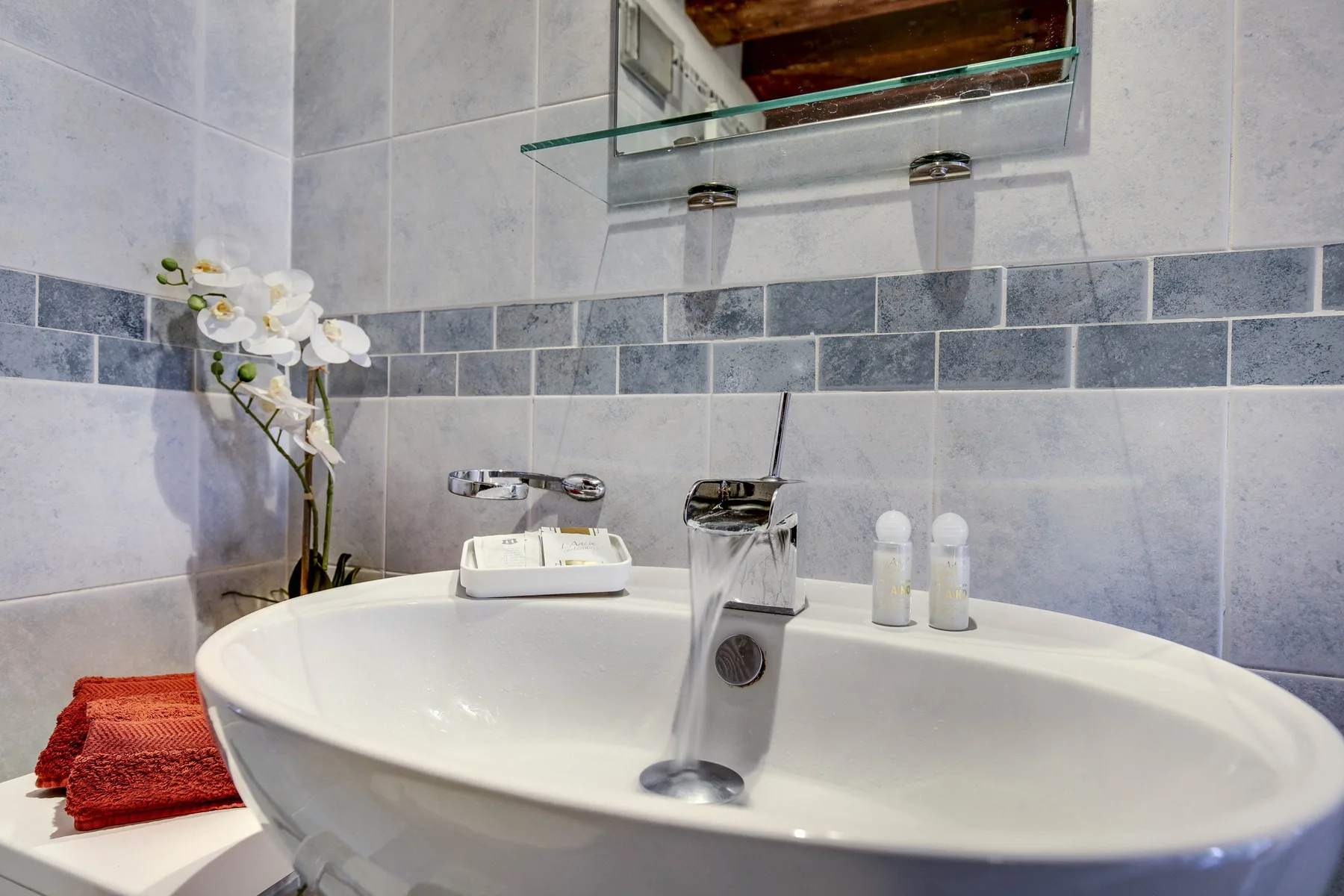 A bathroom sink with a chrome faucet, toiletries, and flowers.
