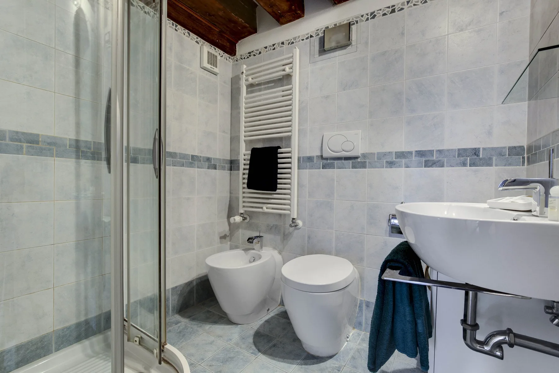 A tiled bathroom with a shower, toilet, bidet, and sink.