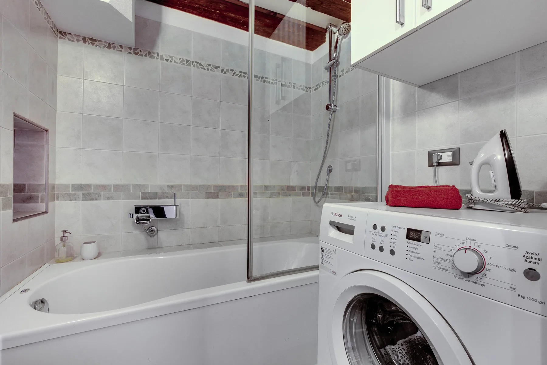 A tiled bathroom with a bathtub, shower, and washing machine.
