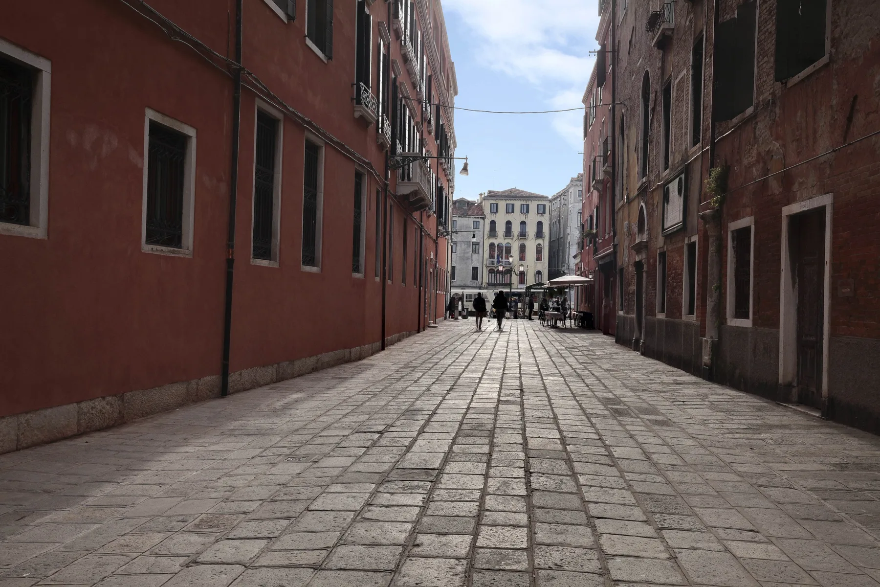 A paved street runs between tall buildings toward a small square.