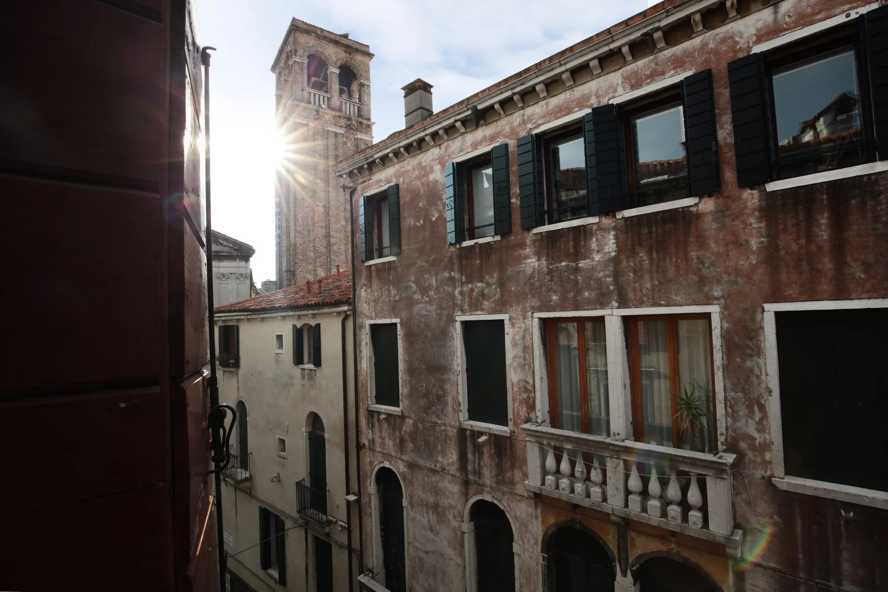 A narrow urban street is lined with weathered buildings and shuttered windows.