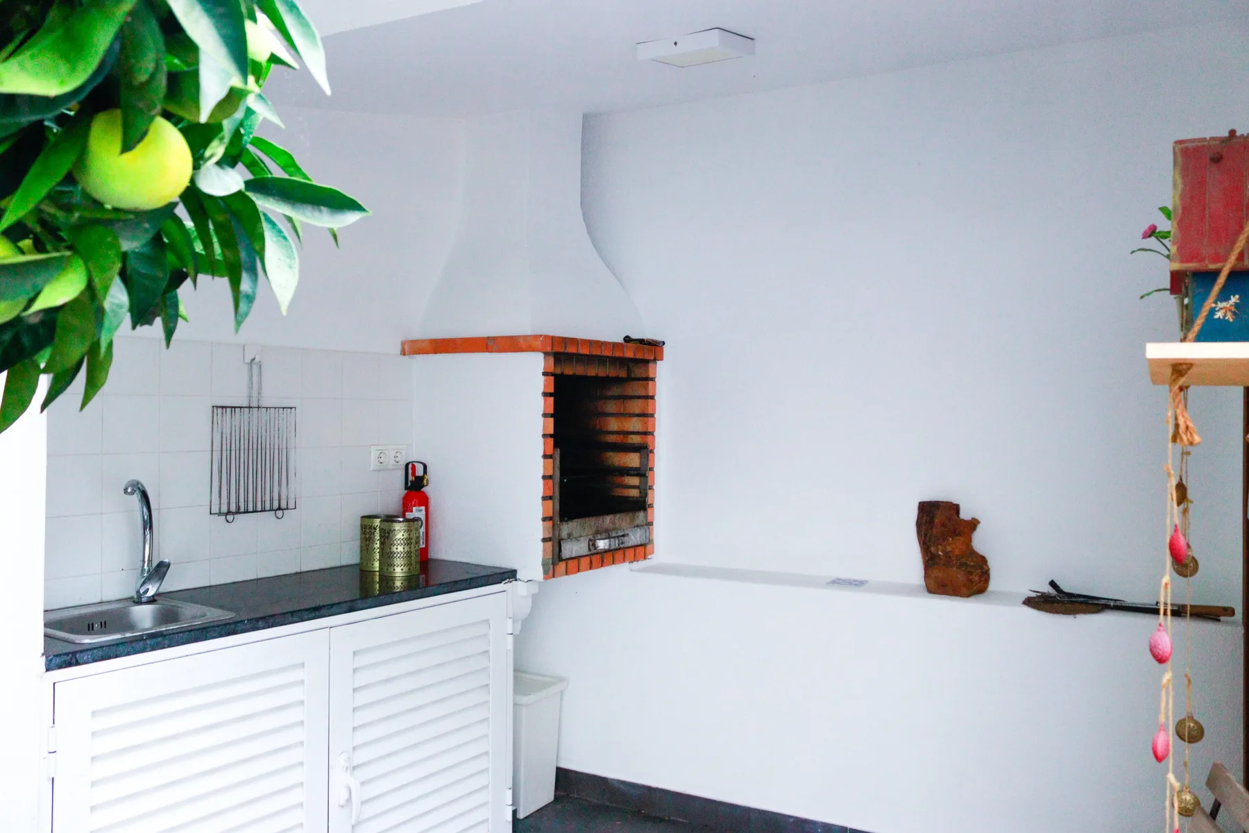 A white-tiled kitchen area with a counter and wall-mounted grill.