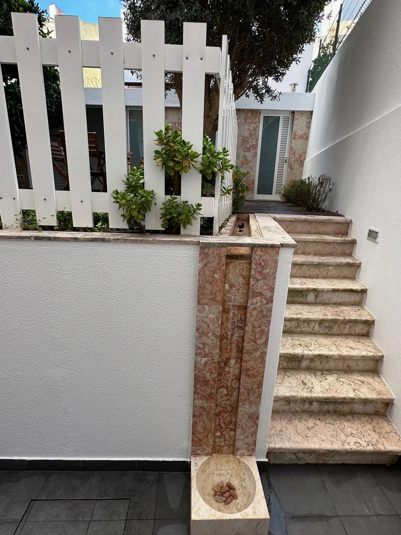 An outdoor stairway leads to a small patio beside a white fence.