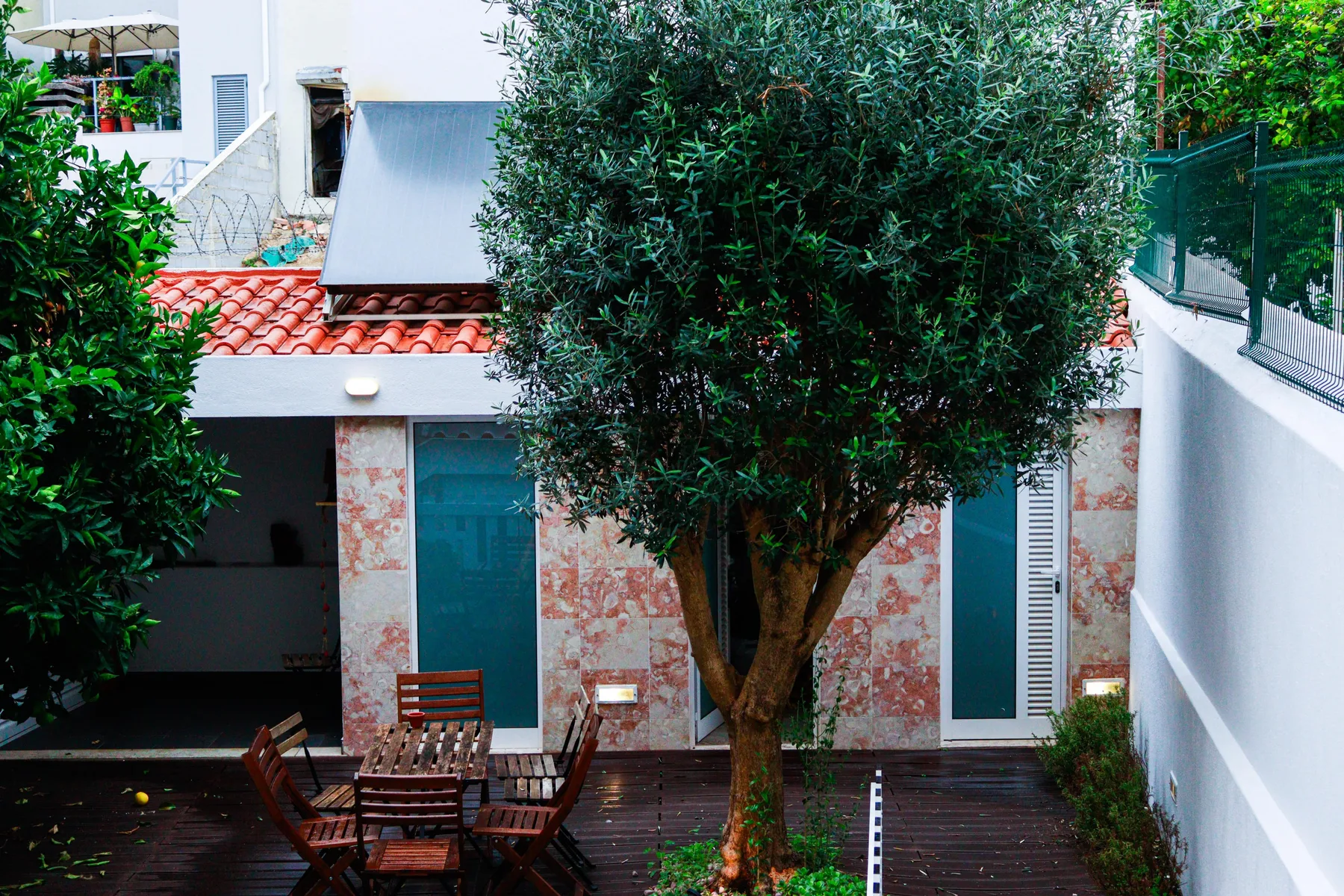 A courtyard with a wooden patio seating area beneath a leafy tree.