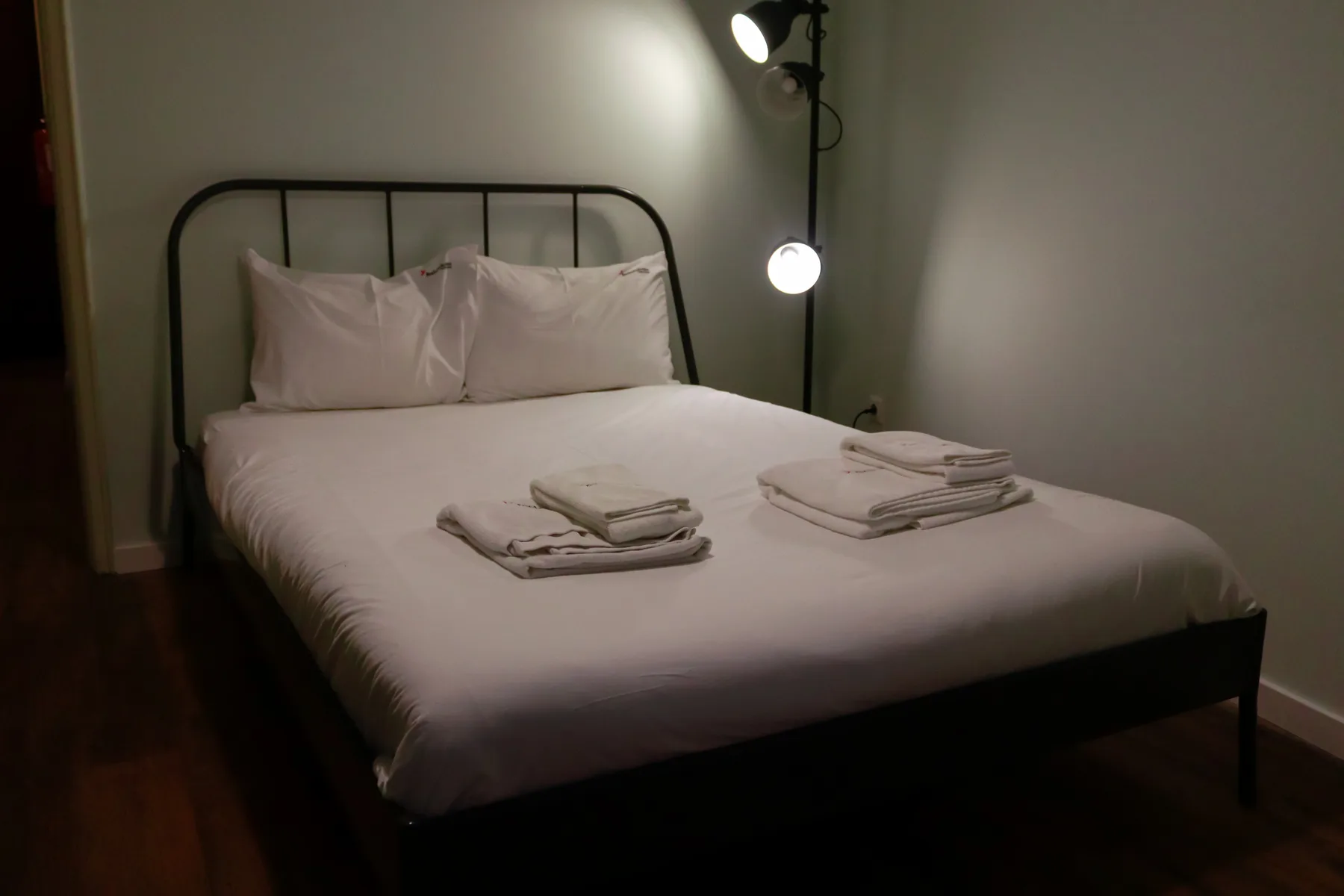 A bedroom with a neatly made bed and folded towels.