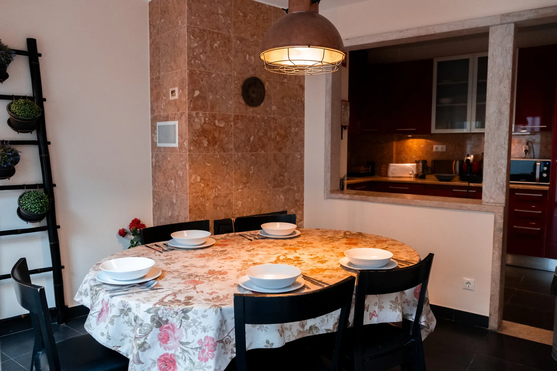 A dining area with a floral tablecloth and a view into the kitchen.