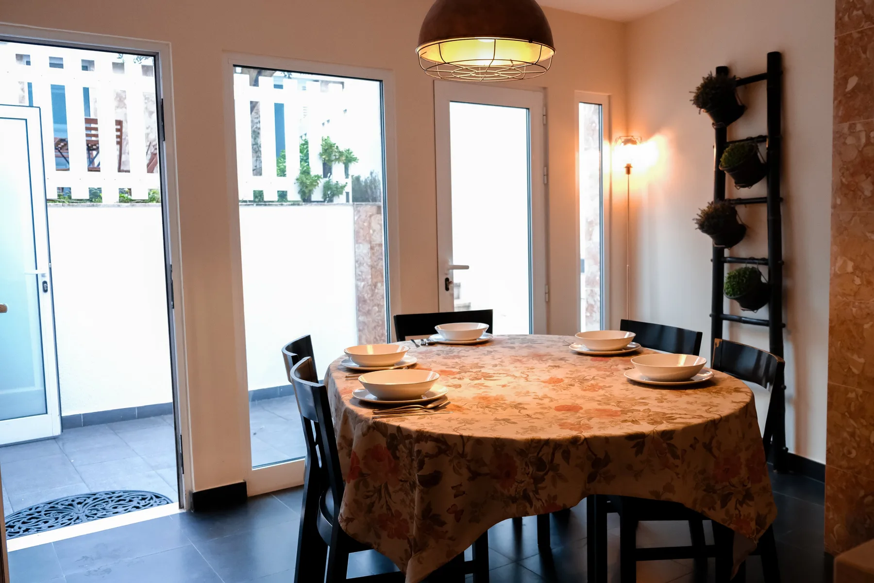 A dining area with a round table set beneath a pendant light.
