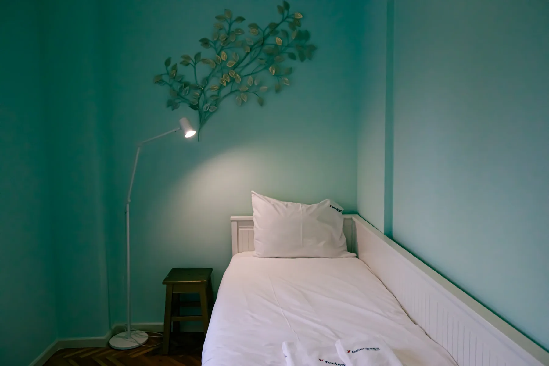 A narrow bedroom with a single bed and a small bedside table.