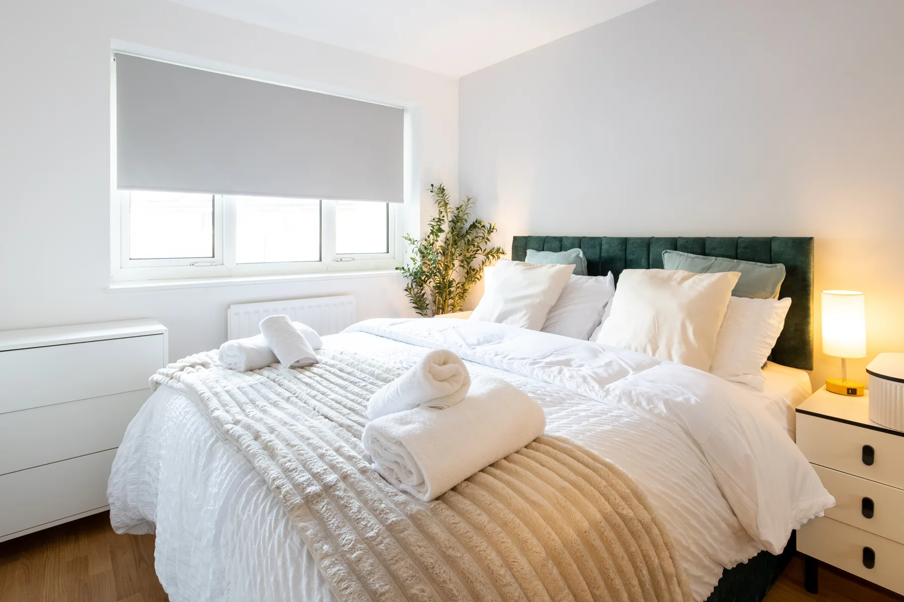A bright bedroom with a neatly made bed and folded towels.