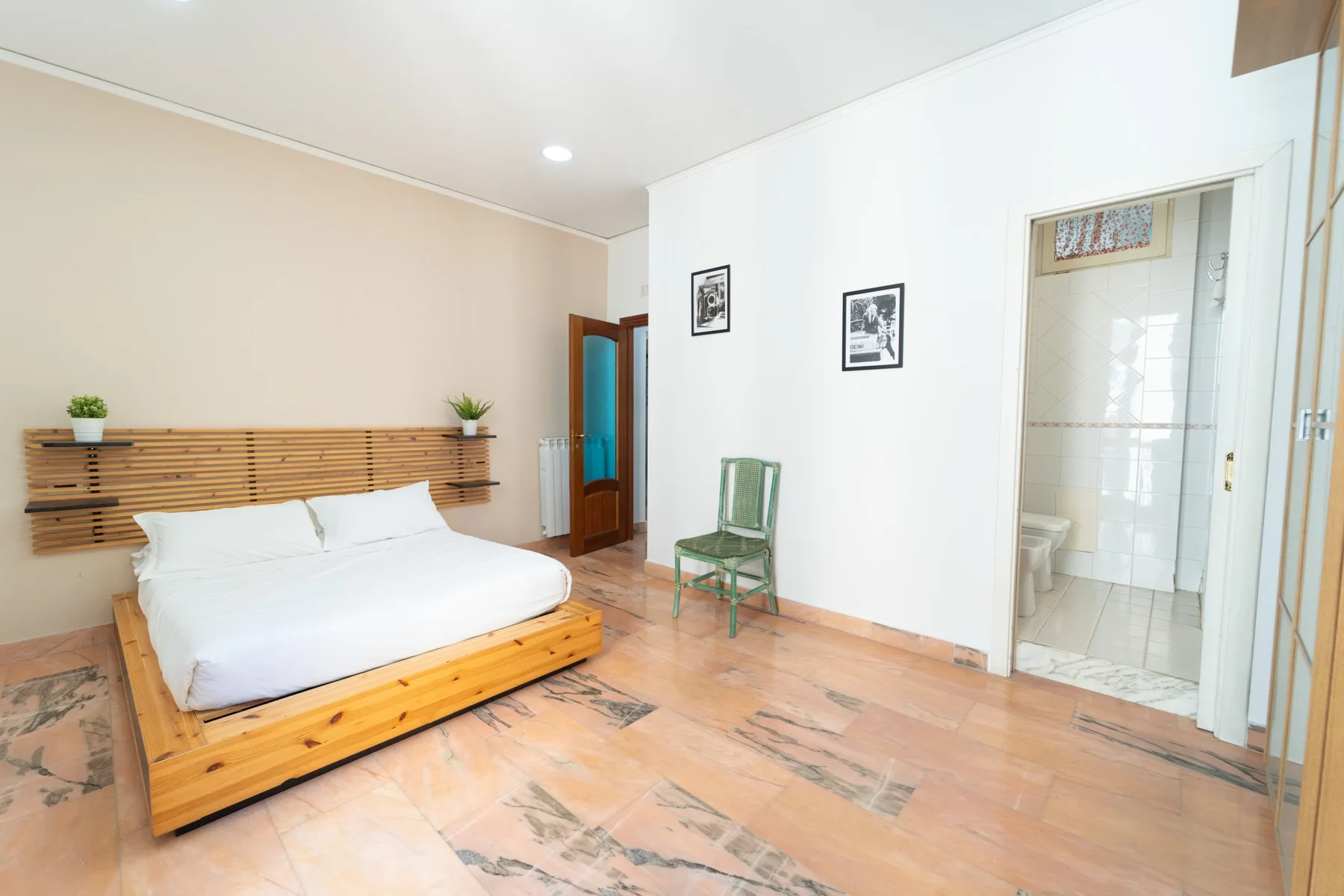 A bright bedroom with a low bed and a doorway to a tiled bathroom.